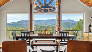 Ein Essbereich mit Bergblick, Holzmöbeln und einer Chandelier.