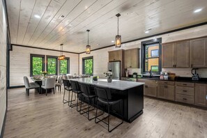 Una cocina moderna con armarios de madera, una isla central, taburetes de bar e iluminación colgante.