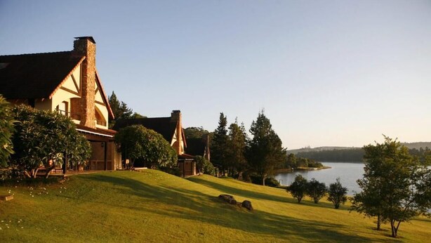 A house with a large lawn and a lake in the background. - Pine Lake Resort (White River)