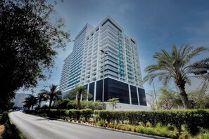 A high-rise hotel with a modern design, featuring a prominent corner entrance and a large glass facade. - Bloomfields Cozy Stu Binghatti (Dubai)