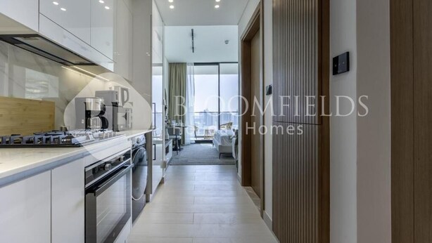 A modern kitchen with white cabinetry, a central island, and a built-in oven. - Bloomfields Cozy Stu Binghatti (Dubai)