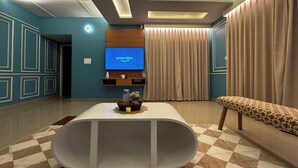 Una sala de estar moderna con un televisor de pantalla plana, una amplia mesa de centro blanca y una alfombra estampada.