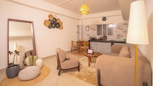 Una sala de estar con sofá, sillas, una mesita de centro, un espejo y una lámpara.