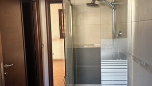 Een moderne badkamer met een douchecabine, een handdoekrek en een fles vloeibare zeep.