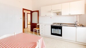 A compact kitchen with white cabinets, a built-in oven, and a sink. - Sea view apartment in the historic center (Castelsardo)