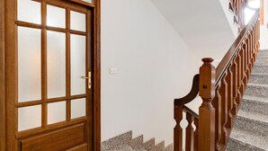 A wooden door with frosted glass panels, a staircase with wooden balusters, and a white wall. - Sea view apartment in the historic center (Castelsardo)