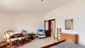 A bedroom with a bed, a desk with chairs, a chair, a dresser, and a mirror. - Sea view apartment in the historic center (Castelsardo)