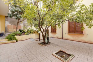 A courtyard with tiled flooring, a tree, and a window with wooden shutters. - Sea view apartment in the historic center (Castelsardo)