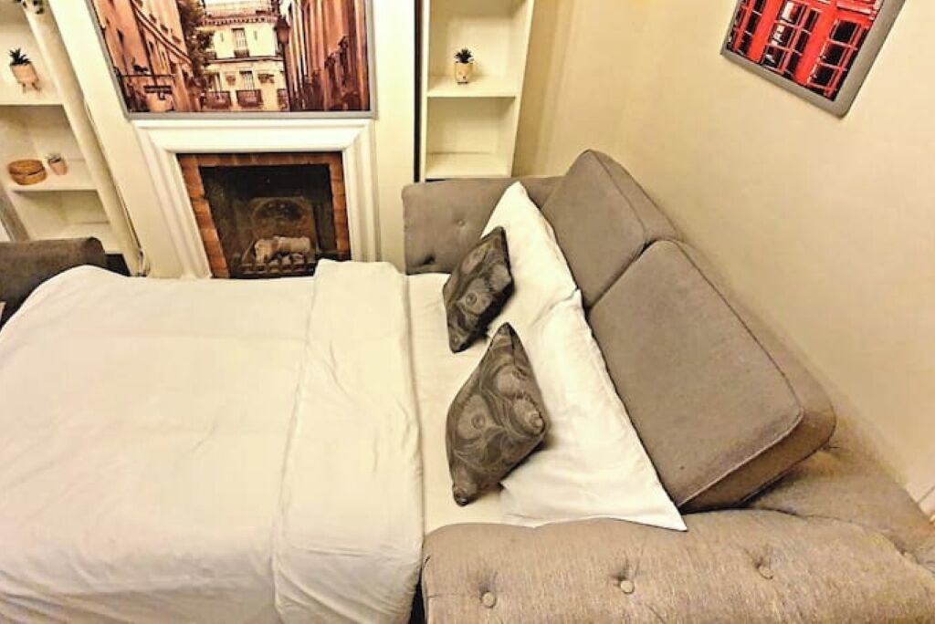 Une chambre à coucher comprenant un lit, un canapé, une cheminée et des étagères ornées d’objets décoratifs.