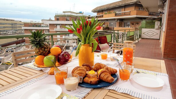 Een ontbijtje op een balkon, met fruit, croissants en sap.