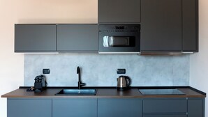 Een moderne keuken met een ingebouwde oven, een koffiezetapparaat en een waterkoker op het aanrecht.