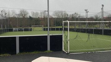 Un campo deportivo con un arco, una banca y una valla.