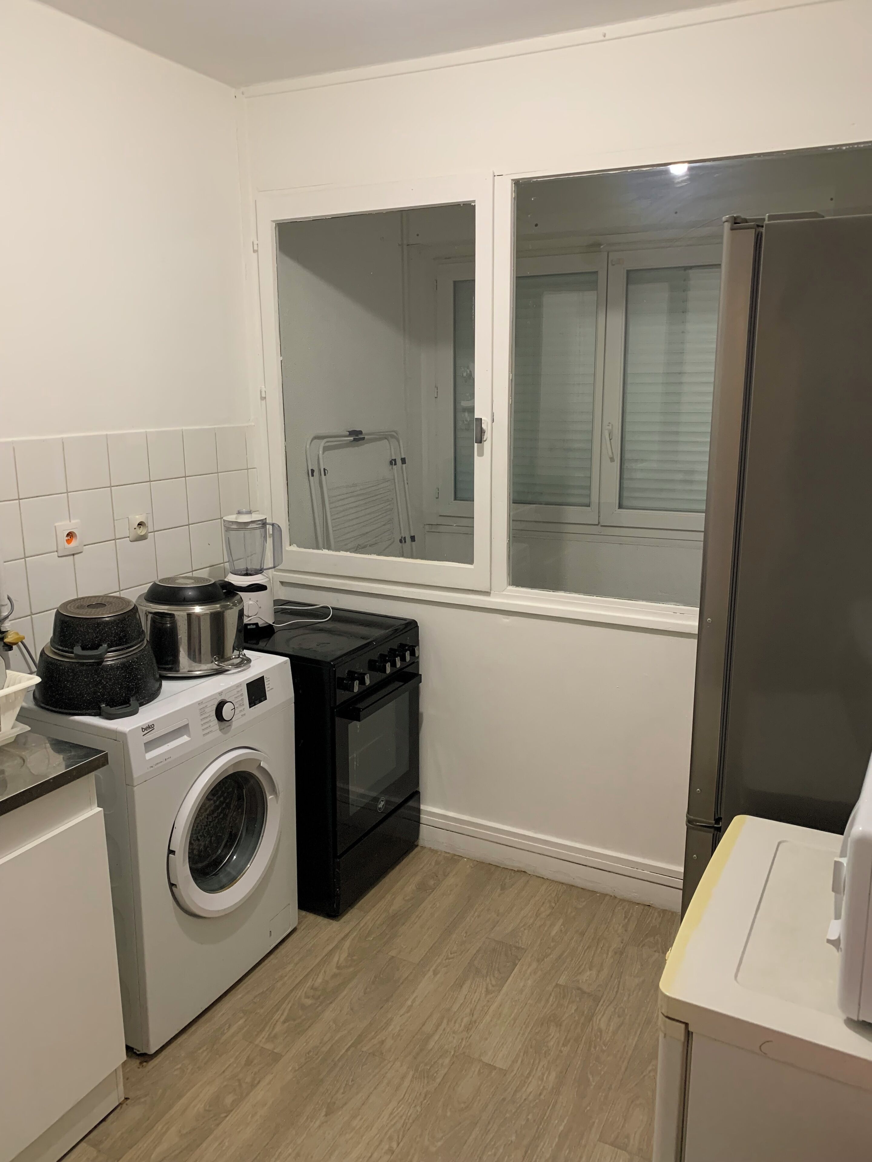 A compact kitchen with a washing machine, a stove, and a refrigerator.