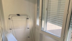 Een smal balkon met twee witte stoelen en een witte radiator.