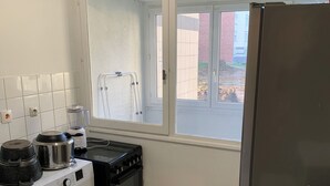 Een kleine keuken met een wasmachine, een fornuis, een magnetron en een koelkast.