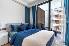A modern hotel room with a large bed, a desk, and a view of a balcony with outdoor furniture. - Sunshine by Villacarte (Choeng Thale)