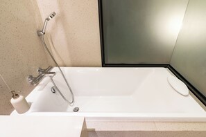 Une salle de bain moderne avec une baignoire blanche, une douchette et un distributeur de savon.
