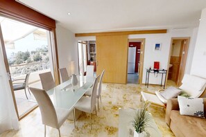 A modern living room with a glass dining table, comfortable seating, and a view of the city. - Sunlit Marbella Apartment Near Sea (Marbella)