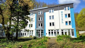 Un hôtel à plusieurs étages au design moderne, dont la façade est ornée d’une grande enseigne indiquant « HÔTEL ».