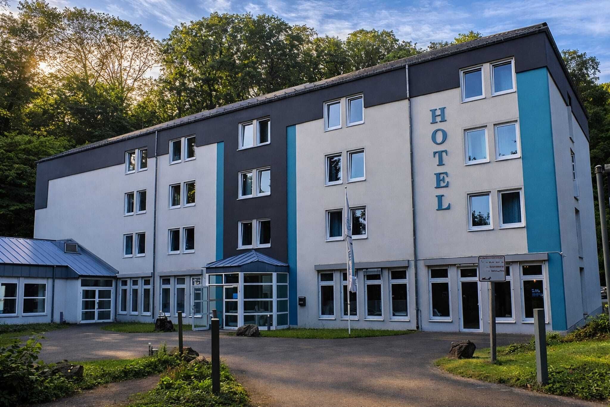 Een hotel met meerdere verdiepingen, met een modern design, vlakke daken, grote ramen en een bord met de naam van het hotel.
