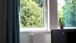 Ein Zimmer mit Fenster, Heizkörper und einem Schrank mit einer Vase aus Schilf.