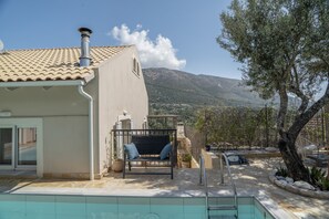 Zona de piscina con un banco, barandilla metálica y vistas a las montañas.
