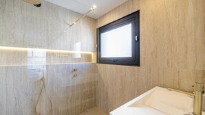 Un baño moderno con ducha, ventana y lavabo.