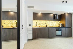 A modern kitchen with dark wood cabinets, a granite backsplash, and built-in appliances. - Renovated Prestige 3P Luxe apt, Terrace & Parking (Cannes)