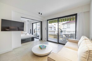 A modern living room with a sofa, a round coffee table, and a TV mounted on the wall. - Renovated Prestige 3P Luxe apt, Terrace & Parking (Cannes)
