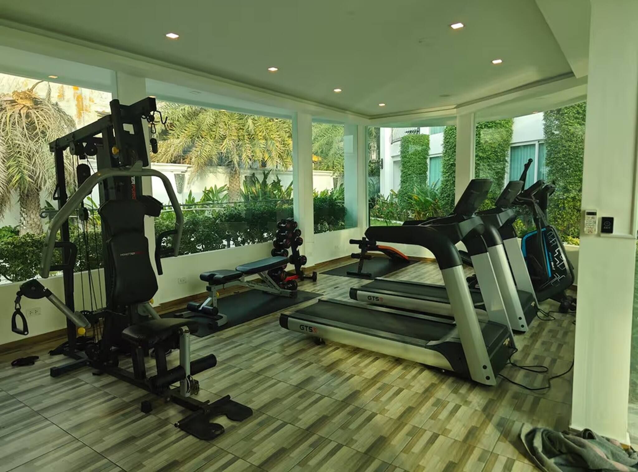 A modern gym with a treadmill, weight bench, and various exercise machines.