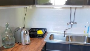 Une cuisine de taille réduite, équipée d’une cuisinière, d’un évier et de meubles de rangement de couleur sombre.