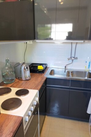 Een koelkast, een oven, kookgerei, borden en bestek