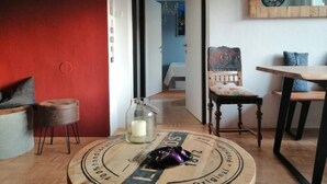 Un salon chaleureux avec un mur d’accent rouge, une table basse ronde au design vintage, une chaise en bois et une table à manger.