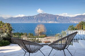 Une terrasse avec deux chaises donnant sur un plan d’eau et des montagnes.