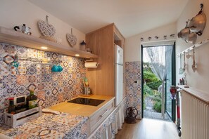 A kitchen with patterned tiles, a wooden counter, and a view of a garden through a glass door. - The Nest (Castelletto)