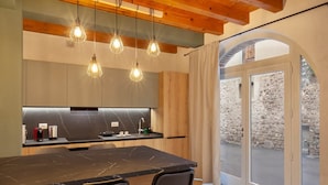 A modern kitchen with a marble countertop, wooden cabinets, and pendant lighting. - Bohemia Apartment (Calmasino)