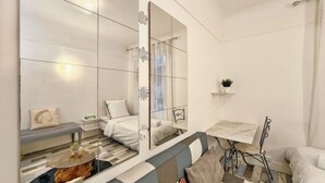 Una habitación de hotel moderna con un espejo grande, una mesa de centro de madera, un sofá y una pequeña mesa con una planta.