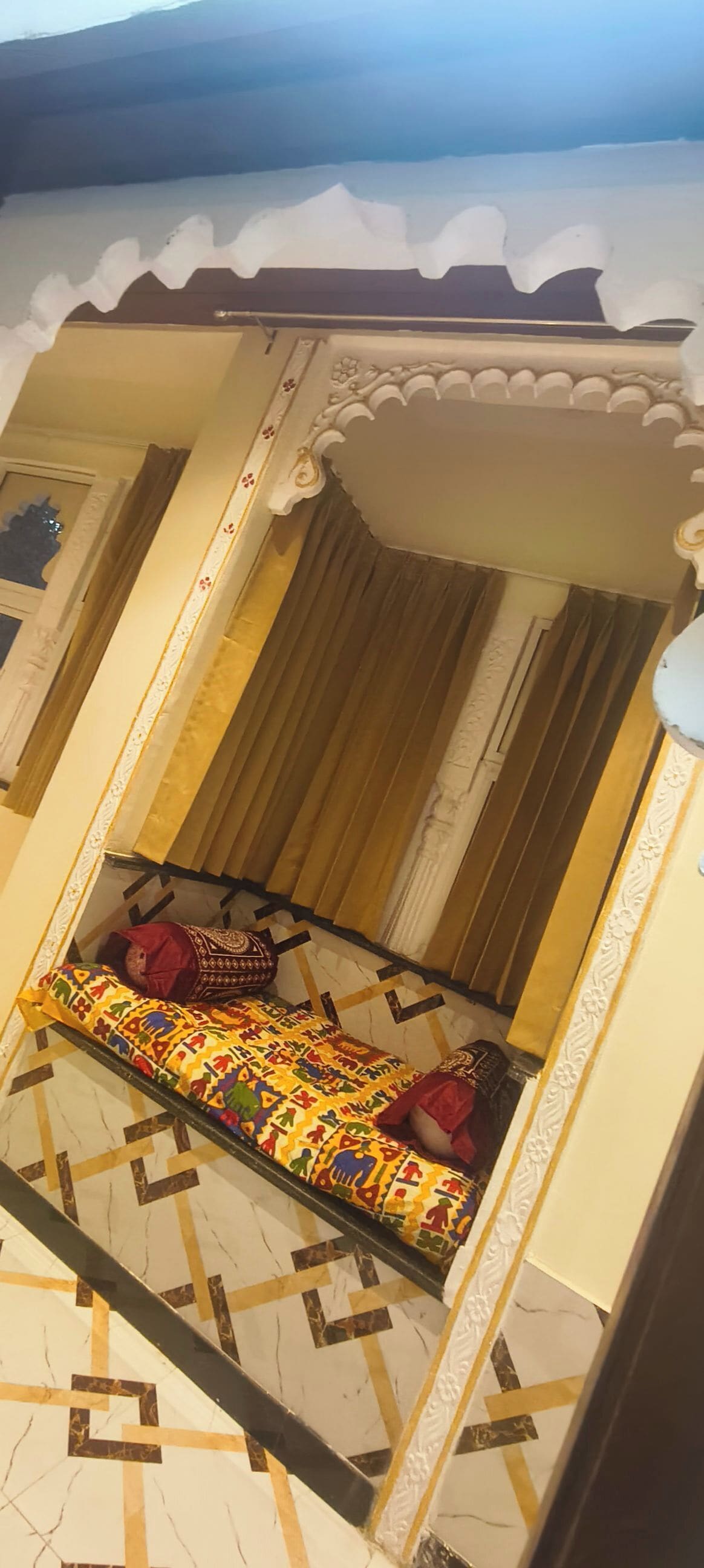 Ein Zimmer mit einem Bett, gemusterten Vorhängen und einem gefliesten Boden.