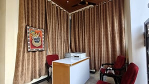 A conference room with a white table, red chairs, a ceiling fan, and a framed picture on the wall. - Shree ji palace  (Udaipur)