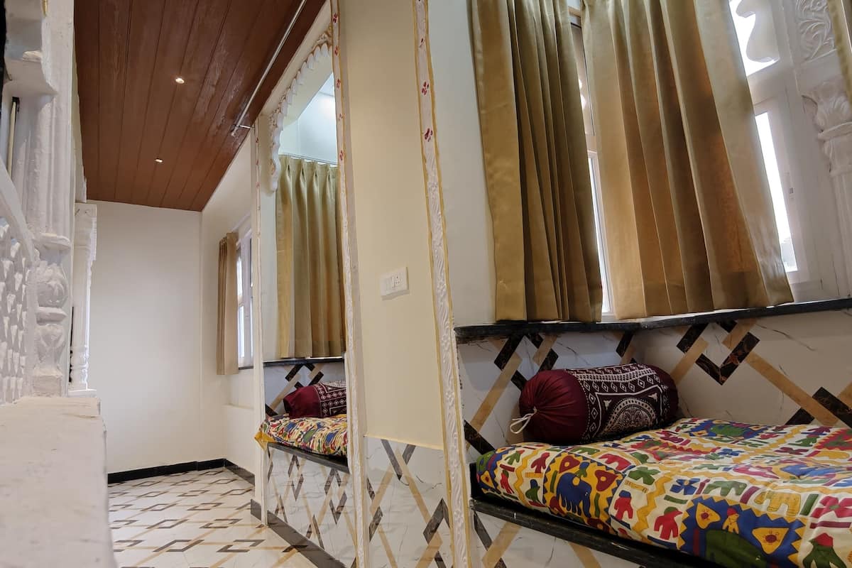 A hotel room with a geometric patterned floor, a wooden ceiling, and a bed with colorful bedding.