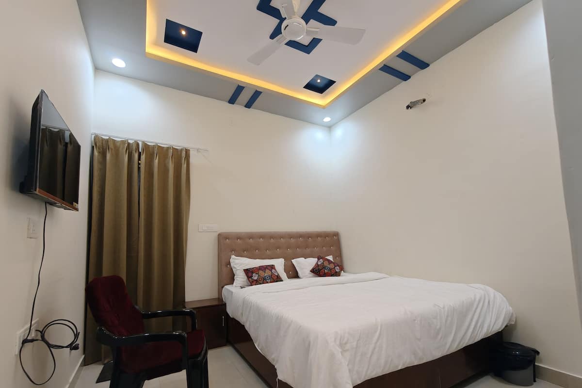 A modern hotel room with a bed, a TV mounted on the wall, a ceiling fan, and a window with curtains.