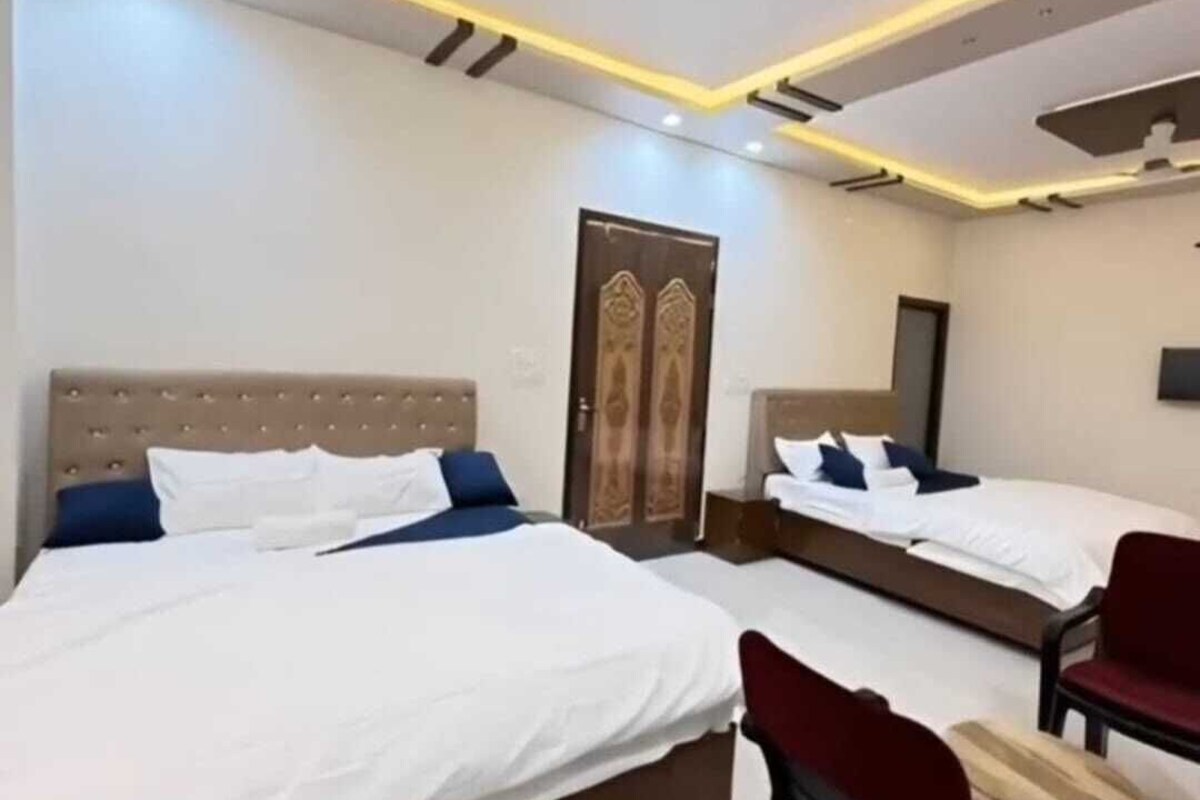 A hotel room with two beds, a red chair, and a ceiling fan.
