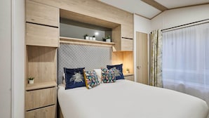 Ein Schlafzimmer mit Bett, Regalen, einem Nachttisch und einem Fenster mit Vorhängen.