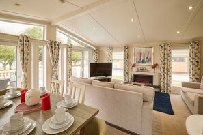 A spacious living room with a sofa set, a television, and a fireplace.