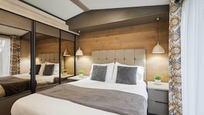 Une chambre à coucher moderne avec un grand lit, des tables de chevet, un miroir et une tête de lit en bois.