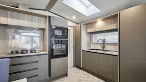Une cuisine moderne dotée d’appareils électroménagers intégrés, d’un puits de lumière et d’une fenêtre avec des stores.