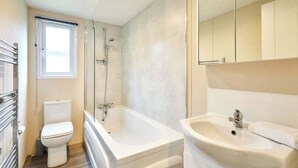 Et moderne badeværelse med toilet, badekar og vask.