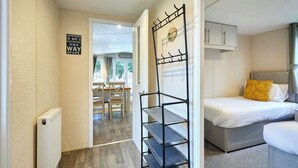 Et soveværelse med seng, et natbord, en radiator, en sort metalreol og et skilt på væggen.
