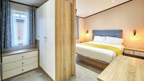 Ett hotellrum med en säng, sängbord, en garderob och ett fönster med gardiner.