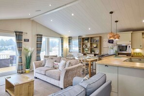 Una sala de estar acogedora con un sofá, una mesa de centro y un comedor con una mesa y sillas. Hay una zona de cocina con un fregadero, estufa y armarios.